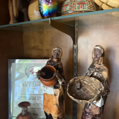 Display shelf featuring handcrafted Mexican papier-mâché or leather figures, small ceramic pots, iridescent art glass, and various global...