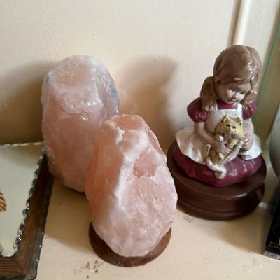 Sale Photo Thumbnail #155: Two natural pink Himalayan salt lamps alongside a painted figurine music box depicting a young girl holding a cat.