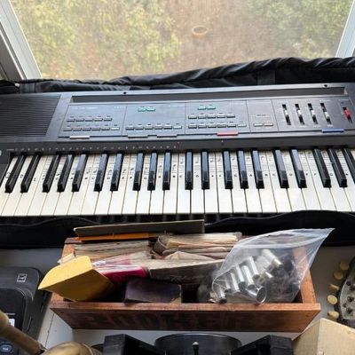 Sale Photo Thumbnail #186: Casio electronic keyboard in a black soft case alongside a wooden organizer box with miscellaneous supplies.