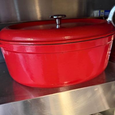 Sale Photo Thumbnail #369: Red enameled cast iron oval Dutch oven with matching lid and metal knob.