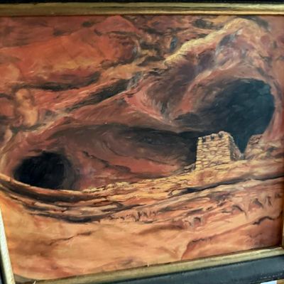 Sale Photo Thumbnail #80: Framed Southwestern landscape oil painting depicting red rock alcoves and stone ruins, set in a dark wood frame with gold inner lip.