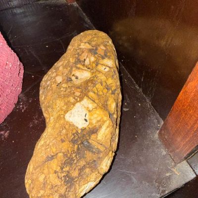 Sale Photo Thumbnail #130: Large natural stone or conglomerate rock specimen, displayed on a wooden shelf.