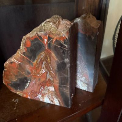 Sale Photo Thumbnail #136: Pair of polished petrified wood bookends displaying vibrant red, orange, and dark brown tones with natural rough edges.