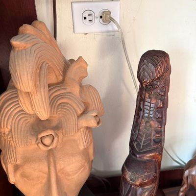 Sale Photo Thumbnail #208: Terracotta Mayan-style bust sculpture alongside a carved dark wood figurine with metal wire embellishments.