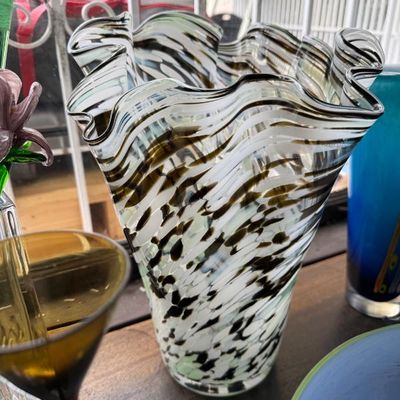 Sale Photo Thumbnail #26: Handblown glass vase featuring a ruffled rim and a swirled black, white, and clear pattern.