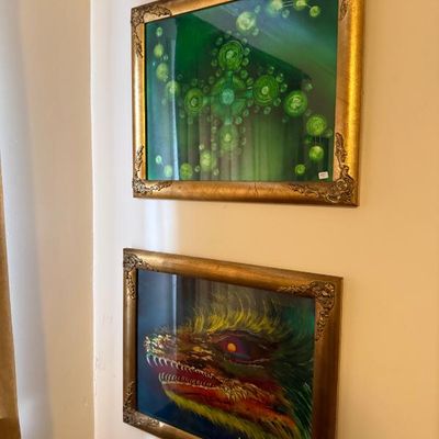 Sale Photo Thumbnail #121: Pair of framed surrealist artwork prints depicting a green abstract design and a dragon's face, housed in ornate gilded frames.