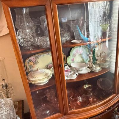 Sale Photo Thumbnail #337: Traditional wooden china cabinet with glass doors, displaying a collection of vintage glassware, cut crystal, and floral porcelain serving pieces.
