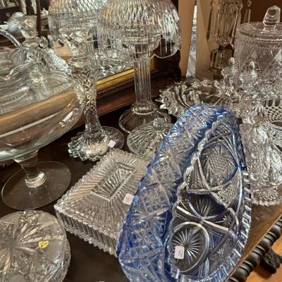 Sale Photo Thumbnail #341: Assorted vintage cut crystal glassware, featuring a blue cut-to-clear oval bowl, hurricane lamps, covered dishes, and candlesticks.