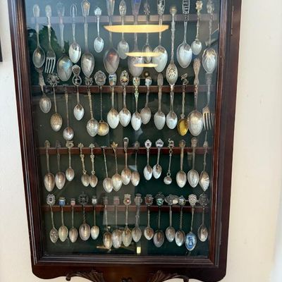 Sale Photo Thumbnail #313: Wall-mounted wooden display case filled with a large collection of vintage souvenir spoons and small forks.