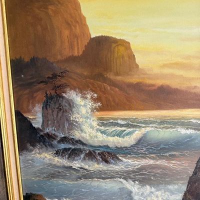 Sale Photo Thumbnail #89: Framed oil painting depicting crashing ocean waves against a rocky coastline bathed in warm sunset light.