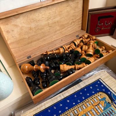 Sale Photo Thumbnail #173: Vintage wooden chess set stored inside its original hinged wooden box, featuring light and dark carved pieces with felted bottoms.