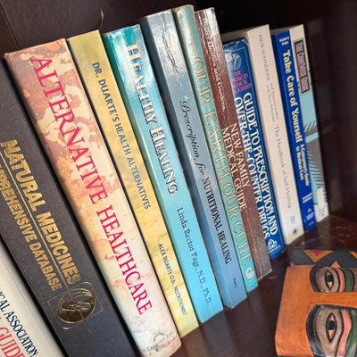 Sale Photo Thumbnail #246: Collection of health, wellness, and alternative medicine reference books arranged on a wooden shelf.