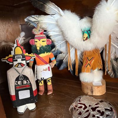 Sale Photo Thumbnail #234: Collection of three hand-carved Hopi-style Katsina dolls adorned with feathers, fur, and leather, shown alongside a filigree heart-shaped silver trinket box.