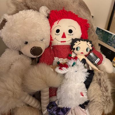 Sale Photo Thumbnail #163: Assortment of plush toys and dolls including a large beige teddy bear, a classic Raggedy Ann doll, and a Betty Boop plush sitting in a faux fur armchair.