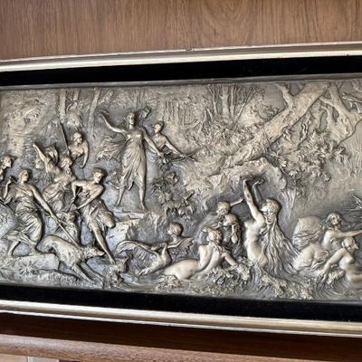 Sale Photo Thumbnail #284: Framed relief plaque depicting Diana the Huntress and nymphs, cast in metal with a silvered finish and set within a silver-toned frame with black velvet trim.