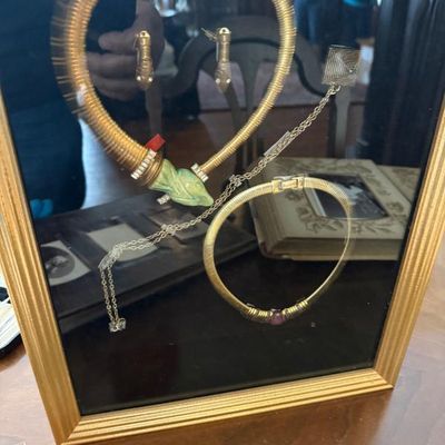 Sale Photo Thumbnail #41: Framed display of vintage Egyptian Revival gold-tone jewelry, including a snake motif collar necklace with a green carved head, matching serpent earrings, a fine chain, and a flexible mesh bracelet.