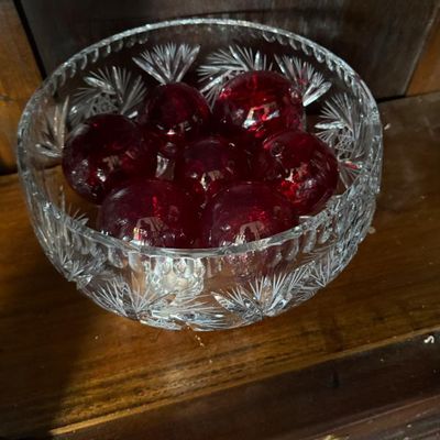 Sale Photo Thumbnail #289: Vintage cut glass bowl filled with red glass decorative spheres, sitting on a wooden cabinet shelf.