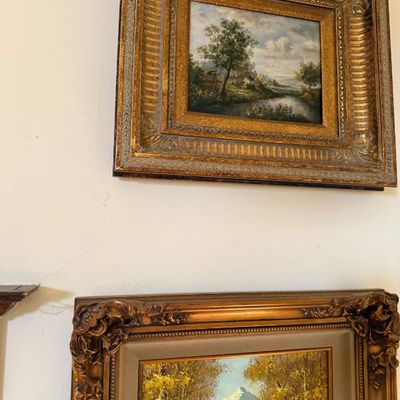 Sale Photo Thumbnail #116: Two framed landscape oil paintings in ornate gold-finished frames, including a pastoral river scene and an autumnal mountain view.