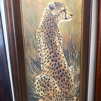 Sale Photo Thumbnail #102: Framed oil painting of a seated cheetah in tall grass, signed by the artist in the lower left corner and housed in a dark wood frame with gilt accent line.
