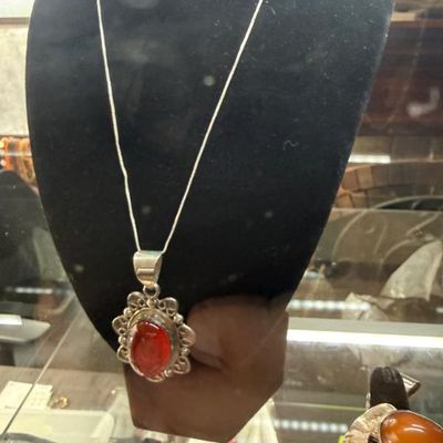 Sale Photo Thumbnail #36: Sterling silver necklace featuring a scalloped pendant set with a polished red cabochon stone, displayed on a black velvet bust.
