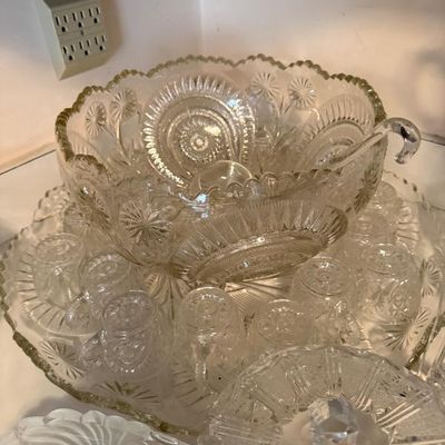 Sale Photo Thumbnail #305: Vintage pressed glass punch bowl set with matching cups, underplate, and glass ladle, featuring intricate pinwheel and starburst patterns.