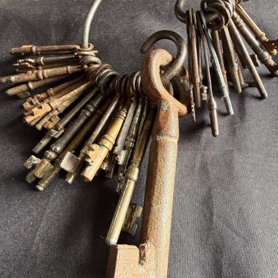 Sale Photo Thumbnail #175: Collection of antique metal skeleton keys on a large iron key ring, featuring varied sizes, patinas, and ages.
