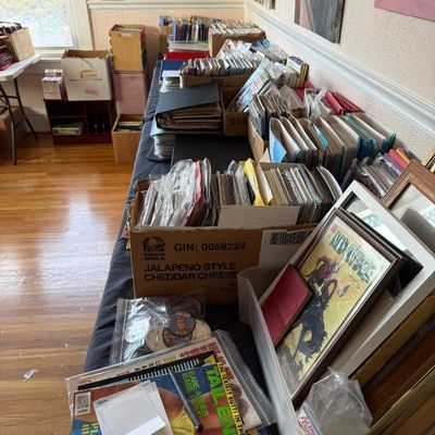 Sale Photo Thumbnail #193: Long table display filled with vintage comic books, adult magazines, vinyl records, and framed art prints.
