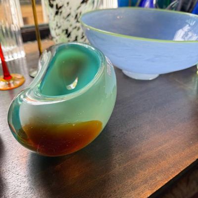 Sale Photo Thumbnail #27: Collection of art glass pieces, featuring a mid-century Murano style organic sommerso glass bowl in teal and amber alongside a pale blue frosted glass bowl.