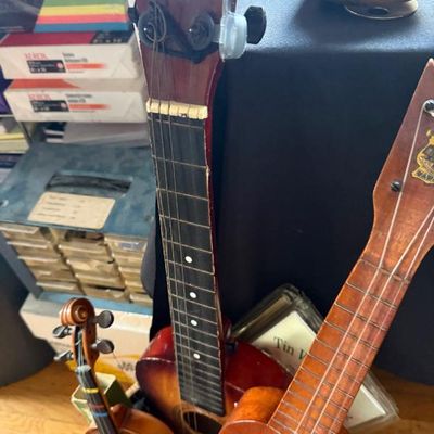 Sale Photo Thumbnail #182: Collection of stringed musical instruments, including two wooden ukuleles and a miniature decorative violin with bow.