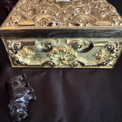 Sale Photo Thumbnail #3: Vintage ornate gold-tone metal trinket box with detailed scrollwork alongside small carved animal figurines.