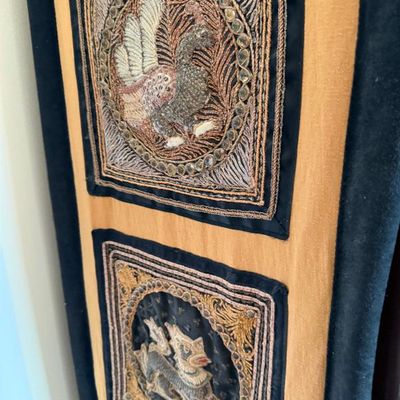 Sale Photo Thumbnail #127: Intricately embroidered Kalaga wall hanging featuring raised metallic metallic-thread panels depicting a peacock and mythological creature set against a gold fabric backing.