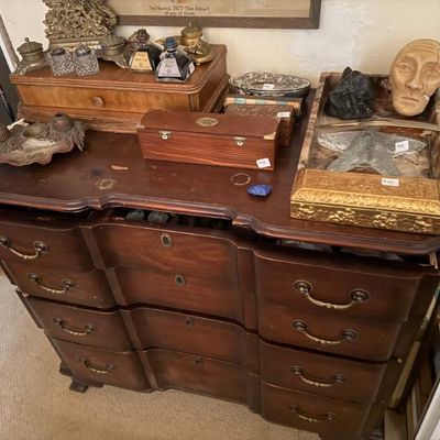 Sale Photo Thumbnail #172: Vintage dark wood blockfront dresser featuring various collectible items, inkwells, small boxes, and decorative objects displayed on top.
