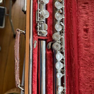 Sale Photo Thumbnail #184: Silver-plated flute disassembled inside its original red velvet-lined hardshell carrying case with leather handle.