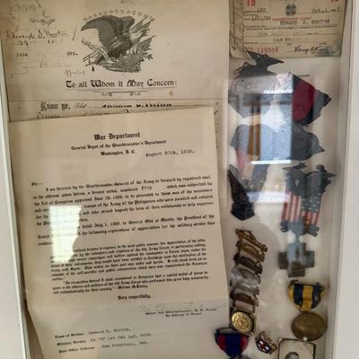 Sale Photo Thumbnail #277: Framed military shadow box containing early 20th-century War Department documents, medals, ribbons, a VFW membership card, and a portrait photo.
