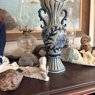 Sale Photo Thumbnail #264: Asian-style blue and beige ceramic vase with crackle glaze finish, displayed alongside clear glass oil lamps and decorative figurines.
