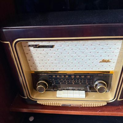 Sale Photo Thumbnail #177: Vintage Grundig Majestic Hi-Fi tube radio in a dark wood cabinet with cream speaker grille fabric and brass accents, circa 1950s.