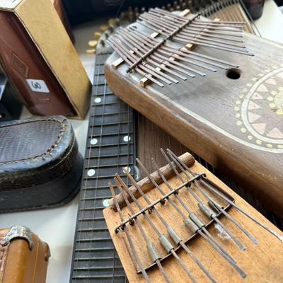 Sale Photo Thumbnail #185: Collection of vintage string and percussion instruments, including two wooden kalimbas and a fretboard, showing light wear.