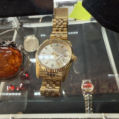Sale Photo Thumbnail #39: Men's gold-tone Croton automatic wristwatch featuring a textured silver-tone dial with diamond hour markers and a fluted bezel, displayed on a jubilee bracelet inside a glass showcase.