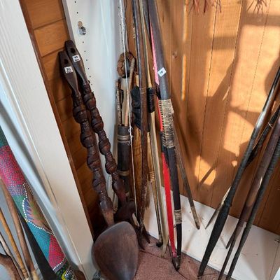 Sale Photo Thumbnail #223: Collection of tribal and ethnographic art, including carved wooden ceremonial spoons, bows, arrows, and painted didgeridoos or spears.