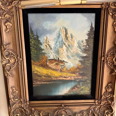 Sale Photo Thumbnail #64: Framed oil painting on canvas depicting an Alpine mountain scene with a cabin and lake, signed 'Keller' in the lower right, housed in an ornate gilded Rococo-style frame with picture light attached.