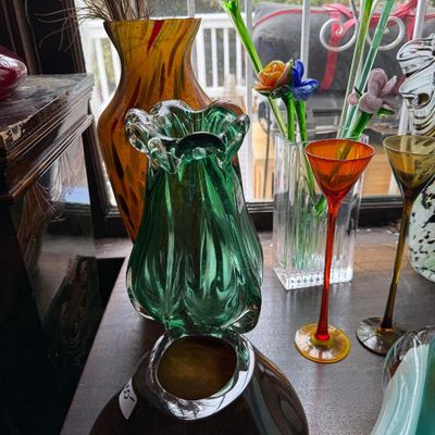 Sale Photo Thumbnail #28: Collection of art glass items, including a green ruffled vase, long-stemmed colorful glass flowers, and delicate cordials.