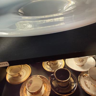 Sale Photo Thumbnail #329: Large light blue art glass console bowl displayed above a shelf filled with assorted vintage porcelain demitasse teacups and saucers.