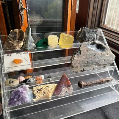 Sale Photo Thumbnail #137: Collection of mineral specimens and geological samples, including amethyst, malachite, and carnelian, displayed on a tiered acrylic stand.