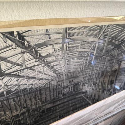 Sale Photo Thumbnail #108: Framed black-and-white architectural photo depicting the interior framework and exposed steel beams of a large industrial warehouse or hangar.