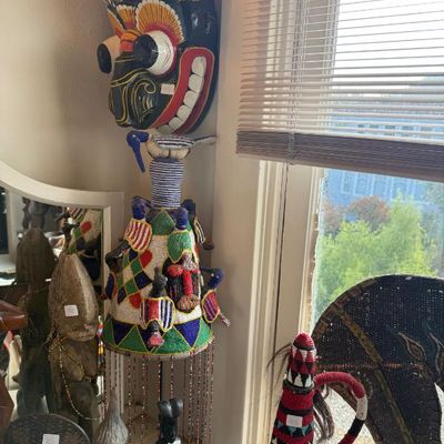 Sale Photo Thumbnail #228: Collection of African tribal art objects, including a Yoruba beaded king's crown, a colorful Sri Lankan Raksha mask, and carved wooden statues.