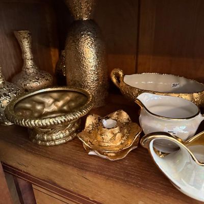 Sale Photo Thumbnail #347: Collection of vintage gold-gilded ceramic decor items, including textured vases, bowls, candle holders, and creamers displayed inside a wooden cabinet.