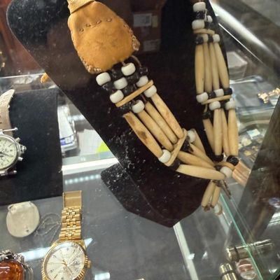 Sale Photo Thumbnail #43: Native American style bone hairpipe chocker necklace with leather spacers and accents, displayed alongside wristwatches in a glass case.