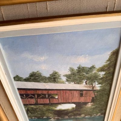 Sale Photo Thumbnail #65: Framed oil painting depicting a rustic red covered bridge over a river, set in a gilded wood frame with a fabric liner.
