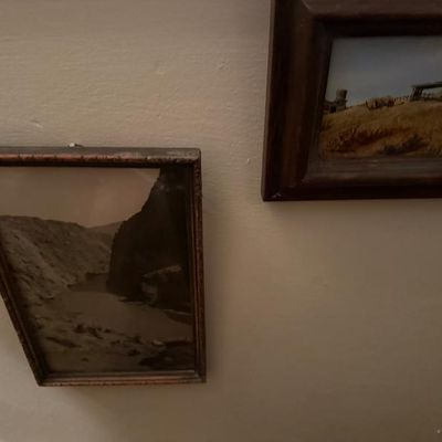 Sale Photo Thumbnail #125: Two framed wall art pieces, including a black-and-white landscape photograph and a small painted scene of a rustic farm in wooden frames.