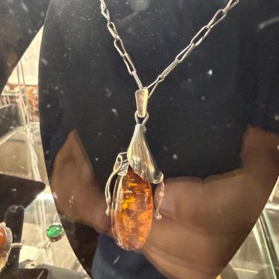 Sale Photo Thumbnail #35: Large amber pendant necklace featuring a sterling silver, leaf-motif setting on a stylized chain.